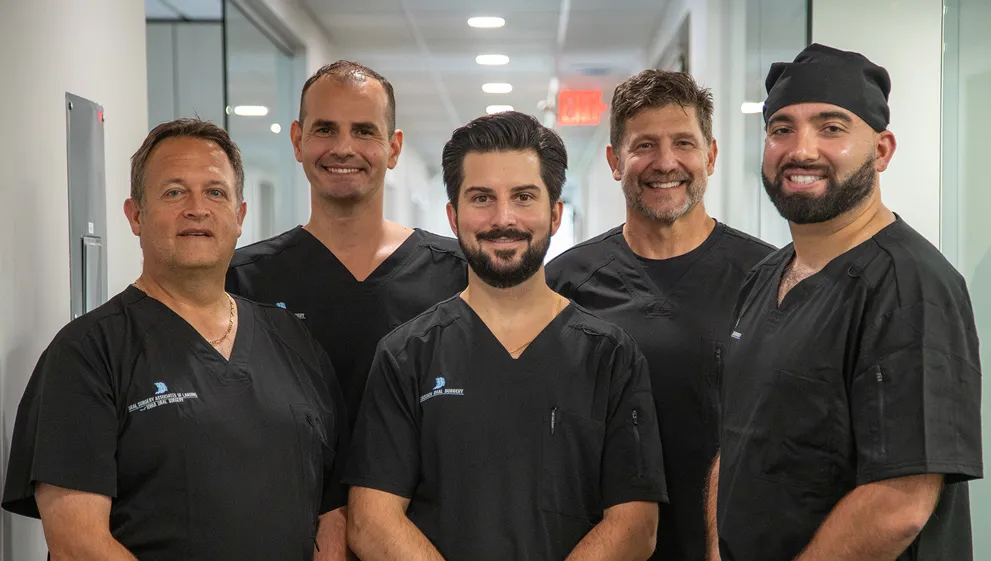 The doctors of oral surgery associates of lansing looking professional in their black scrubs featuring the logo of the practice